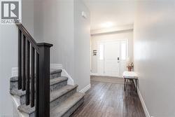 Entryway featuring wood-finish flooring and a white front door with sidelight windows - 