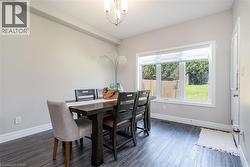 Dining area featuring wood-finish flooring, a large window with roller shades, and a chandelier - 