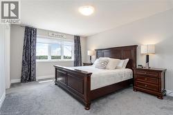 Bedroom featuring light gray wall paint, gray carpet flooring, and a large window with white trim - 