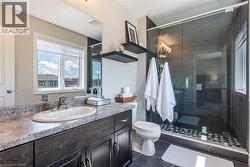 Bathroom featuring a dark wood-finish vanity with an undermount sink and stone-look countertop - 