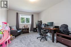 Spacious room featuring light gray walls, plush gray carpeting, a white window frame, and a ceiling-mounted light fixture - 