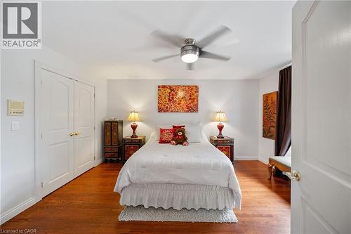 Hardwood flooring extending throughout, ceiling fan with integrated lighting, double-door closet, and white baseboards - 39 Elodia Court, Hamilton, ON 