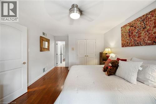 Bedroom featuring wood-finish flooring, a ceiling fan with integrated lighting, and white bi-fold closet doors - 39 Elodia Court, Hamilton, ON 