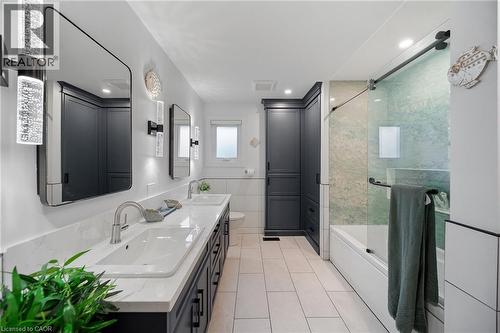 Modern bathroom featuring a double vanity with stone countertops, integrated rectangular sinks, and contemporary wall-mounted light fixtures - 39 Elodia Court, Hamilton, ON 