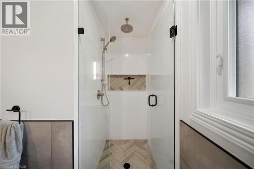 Walk-in shower featuring a glass enclosure with matte black hardware, a rainfall showerhead, and a handheld shower attachment - 39 Elodia Court, Hamilton, ON 