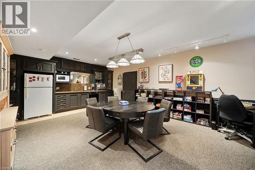 Recessed ceiling lighting illuminates a spacious room featuring a built-in wet bar with dark cabinetry, integrated microwave, and a beverage refrigerator - 39 Elodia Court, Hamilton, ON 