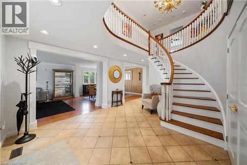Grand foyer featuring a curved staircase with wood treads and a white balustrade - 39 Elodia Court, Hamilton, ON 