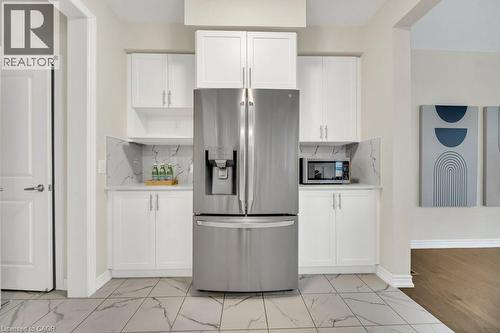 Kitchen with appliances with stainless steel finishes, white cabinetry, and tasteful backsplash - 285 Broadacre Drive, Kitchener, ON 