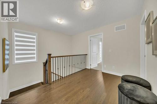 Unfurnished room with wood finished floors, an upstairs landing, and a textured ceiling - 285 Broadacre Drive, Kitchener, ON 