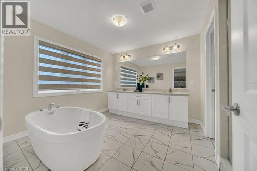 Bathroom with light marble finish flooring, double vanity, and a soaking tub - 285 Broadacre Drive, Kitchener, ON 