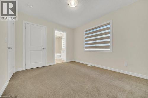Unfurnished bedroom featuring light carpet, ensuite bath, and a textured ceiling - 285 Broadacre Drive, Kitchener, ON 