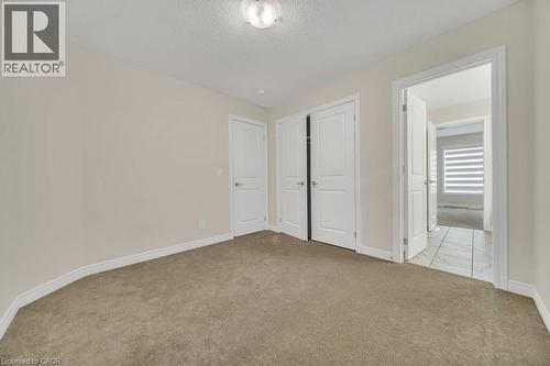 Unfurnished bedroom with light colored carpet, a textured ceiling, and a closet - 285 Broadacre Drive, Kitchener, ON 