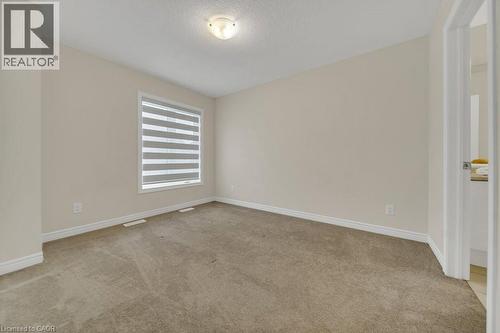 Empty room with light colored carpet and a textured ceiling - 285 Broadacre Drive, Kitchener, ON 