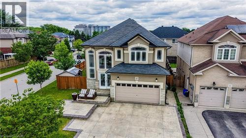 Two-story residence featuring a gray asphalt shingle roof and a stucco exterior with stone accents - 37 Davinci Boulevard, Hamilton, ON 