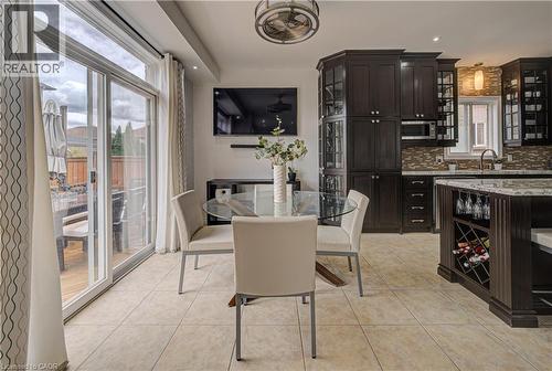 Kitchen and dining area featuring ceramic tile flooring, dark wood cabinetry with glass-front accents, and a built-in wine rack - 37 Davinci Boulevard, Hamilton, ON 