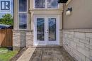 Double entry doors with decorative glass panels, stone veneer facade, stucco exterior, stamped concrete walkway, and an outdoor wall light fixture - 37 Davinci Boulevard, Hamilton, ON 