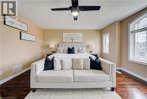 Spacious room featuring wood-finish flooring, a contemporary ceiling fan, and multiple windows - 37 Davinci Boulevard, Hamilton, ON 
