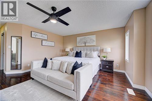 Spacious bedroom featuring dark wood-finish flooring, a contemporary black ceiling fan with integrated lighting, and neutral wall tones - 37 Davinci Boulevard, Hamilton, ON 