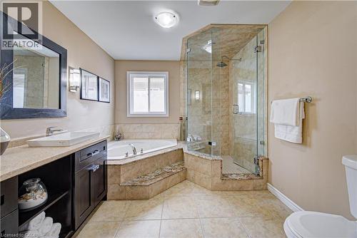 Full bathroom featuring a glass-enclosed shower with tiled walls and a built-in bench, a corner soaking tub with tiled surround, a vanity with a vessel sink and dark wood-finish cabinetry, and tiled f - 37 Davinci Boulevard, Hamilton, ON 