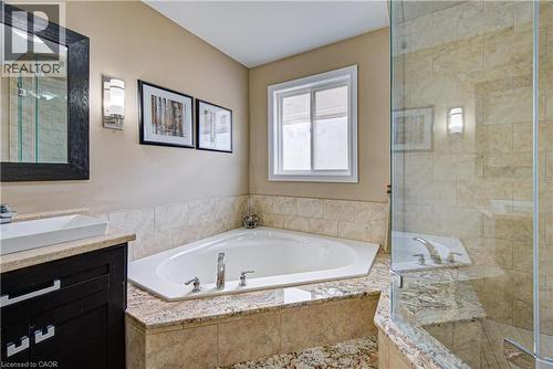 Bathroom featuring an alcove soaking tub, a separate glass-enclosed shower, a dark wood-finish vanity with a vessel sink, and a framed mirror - 37 Davinci Boulevard, Hamilton, ON 