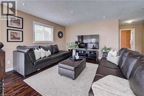 Spacious living area featuring wood-finish flooring, recessed lighting, and ample natural light from a window with blinds - 37 Davinci Boulevard, Hamilton, ON 
