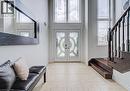 Two-story foyer featuring double entry doors with decorative glass, high transom windows, light-toned tiled flooring, and a dark wood staircase with spindle railing - 37 Davinci Boulevard, Hamilton, ON 