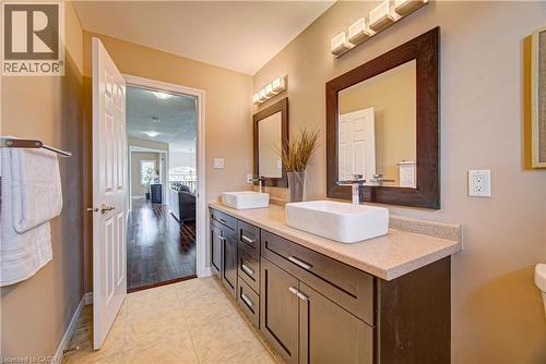 Dual vessel sinks with modern chrome faucets, framed mirrors, and a dark wood-finish vanity - 37 Davinci Boulevard, Hamilton, ON 