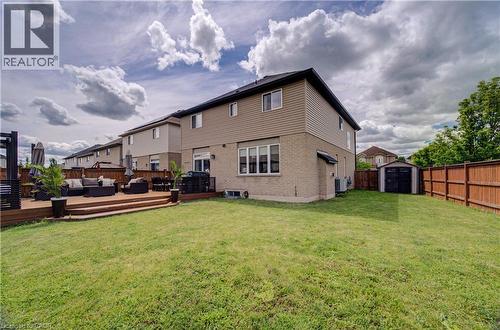 Spacious backyard featuring a multi-level wood deck, a manicured lawn, and a storage shed - 37 Davinci Boulevard, Hamilton, ON 
