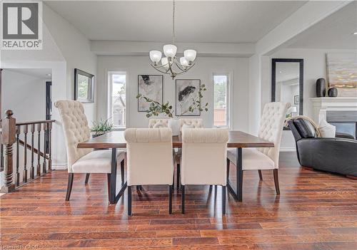 Spacious dining area featuring wood-finish flooring, a contemporary chandelier, and three distinct window panels - 37 Davinci Boulevard, Hamilton, ON 
