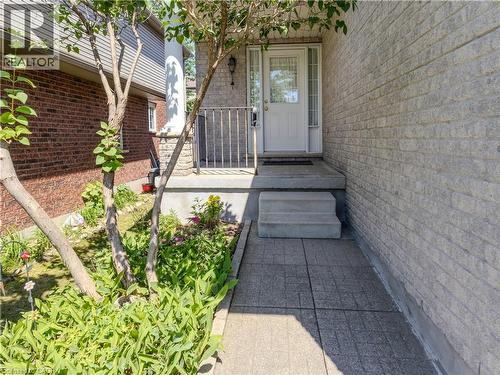 Front entry featuring a white paneled door with decorative glass inserts, a gray brick facade, an entry porch with wrought iron railing, and a patterned concrete walkway - 212 Sleaford Street, Waterloo, ON 