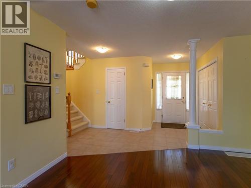 Foyer featuring a white paneled front door with sidelights, a decorative column, and a combination of wood-finish flooring and tile - 212 Sleaford Street, Waterloo, ON 
