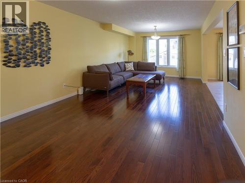Living area featuring extensive wood-finish flooring, light-toned wall paint, and a large multi-pane window - 212 Sleaford Street, Waterloo, ON 