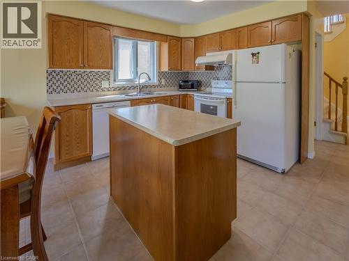 Kitchen featuring wood cabinetry, a central island with a solid surface countertop, tile flooring, and a patterned tile backsplash - 212 Sleaford Street, Waterloo, ON 