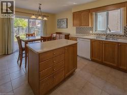 Kitchen featuring wood cabinetry, a center island with drawer storage, a tile backsplash, and a double basin sink - 