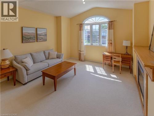 Living area featuring carpet flooring, an arched transom window, vaulted ceiling, and a built-in media console - 212 Sleaford Street, Waterloo, ON 