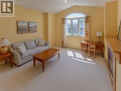 Living area featuring carpet flooring, an arched transom window, vaulted ceiling, and a built-in media console - 