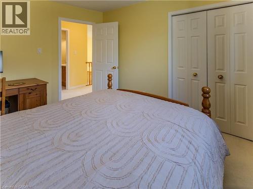 Bright interior featuring light yellow walls, white bi-fold closet doors with brass hardware, and a wood-finish desk - 212 Sleaford Street, Waterloo, ON 
