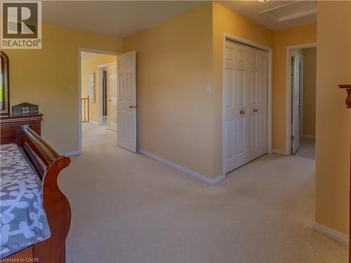 Carpeted room with a double-door closet featuring brass hardware, light-colored walls, and white baseboards - 212 Sleaford Street, Waterloo, ON 