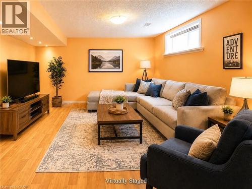 Spacious living area featuring wood-finish flooring, recessed lighting, a window, and a textured ceiling - 212 Sleaford Street, Waterloo, ON 