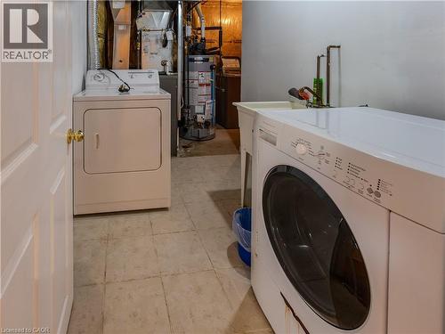 Laundry area featuring a front-loading washing machine, top-loading dryer, and a utility sink - 212 Sleaford Street, Waterloo, ON 