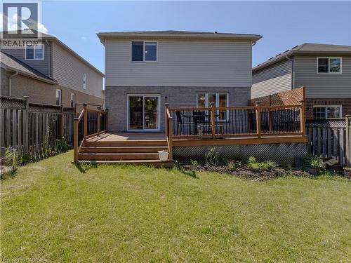Expansive rear yard featuring a large wood-finish deck with black metal balusters, privacy lattice, and direct access to the interior via sliding glass doors - 212 Sleaford Street, Waterloo, ON 