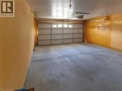 Spacious garage featuring a concrete floor, overhead lighting, and an automatic garage door opener - 212 Sleaford Street, Waterloo, ON 