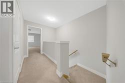 Upper-level hallway with neutral carpeting, light gray wall paint, and white trim - 