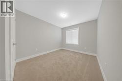 Interior room featuring neutral wall paint, carpet flooring, a window with blinds, a flush mount ceiling light, and white trim - 