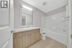 Bathroom featuring a single vanity with wood-finish cabinetry, a light-toned countertop, and a rectangular mirror - 