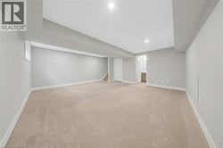 Spacious room featuring neutral carpeting, light gray wall paint, and white trim - 