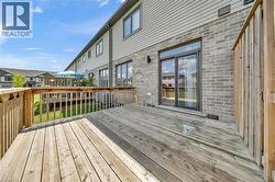 Spacious wooden deck with natural wood railing, grey brick exterior, and a large sliding glass door - 