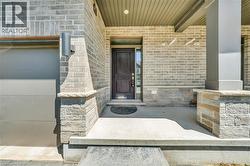 Inviting covered porch with a dark wood-finish entry door, light brick and stone facade, and a complementary garage door - 