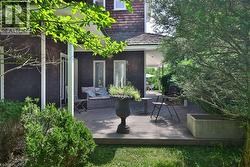 Spacious outdoor deck featuring natural wood-finish flooring, a covered patio area, and mature landscaping - 
