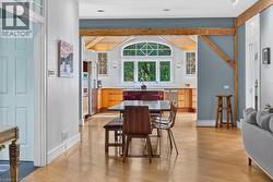 Open-concept living space featuring wood-finish flooring, exposed wood beams, and an arched transom window - 